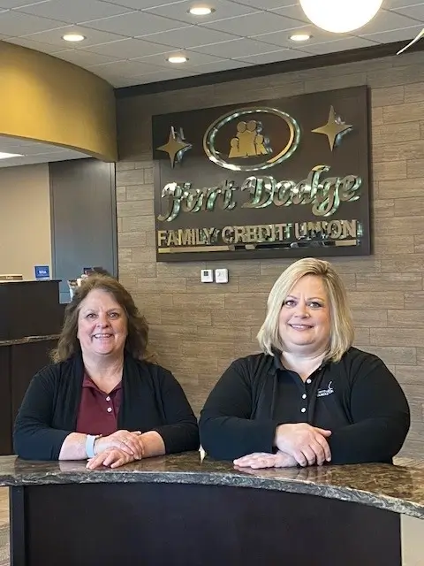 A photograph of Julie Pingel (Credit Union Manager) and Jennifer Alstott (Accountant) standing in the lobby of Fort Dodge Family Credit Union.